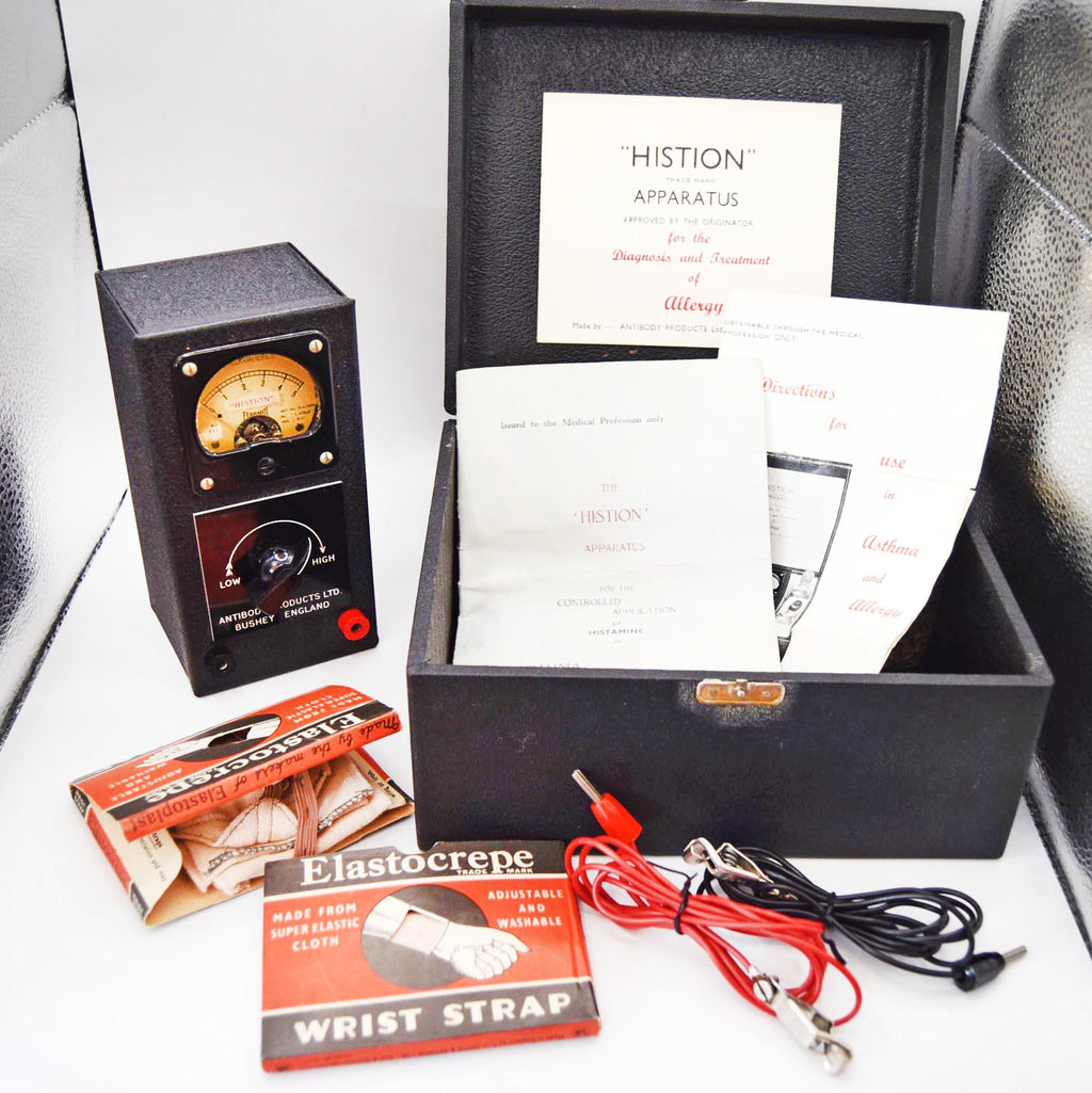 Vintage Histion apparatus kit including a black dial device, open black case with papers, Elastocrepe wrist strap box, red and black wires, and accessories on a white surface.