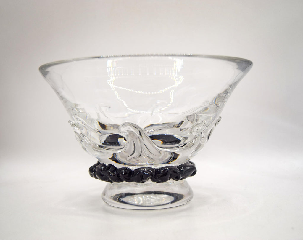 A clear glass bowl with a textured, molded wave-like design on the body and a black twisted rope-style base, shown on a plain light gray background.