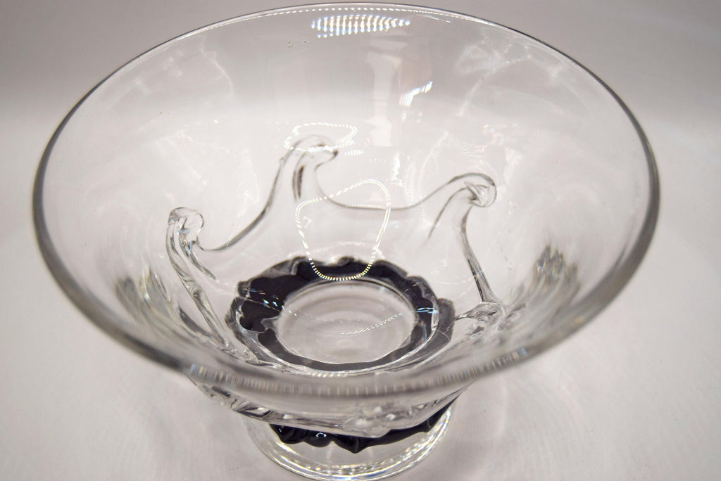 A clear glass bowl with a textured, molded wave-like design on the body and a black twisted rope-style base, shown on a plain light gray background.