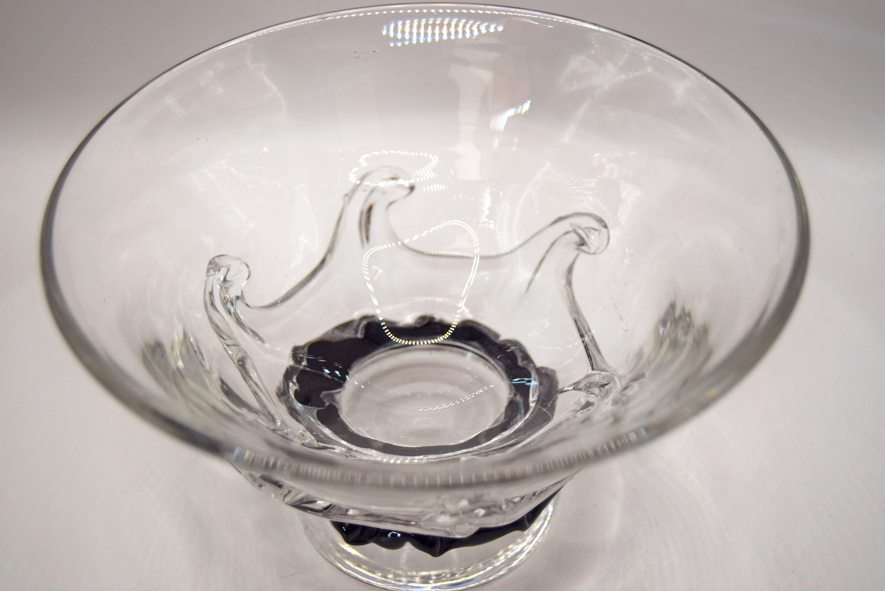 A clear glass bowl with a textured, molded wave-like design on the body and a black twisted rope-style base, shown on a plain light gray background.