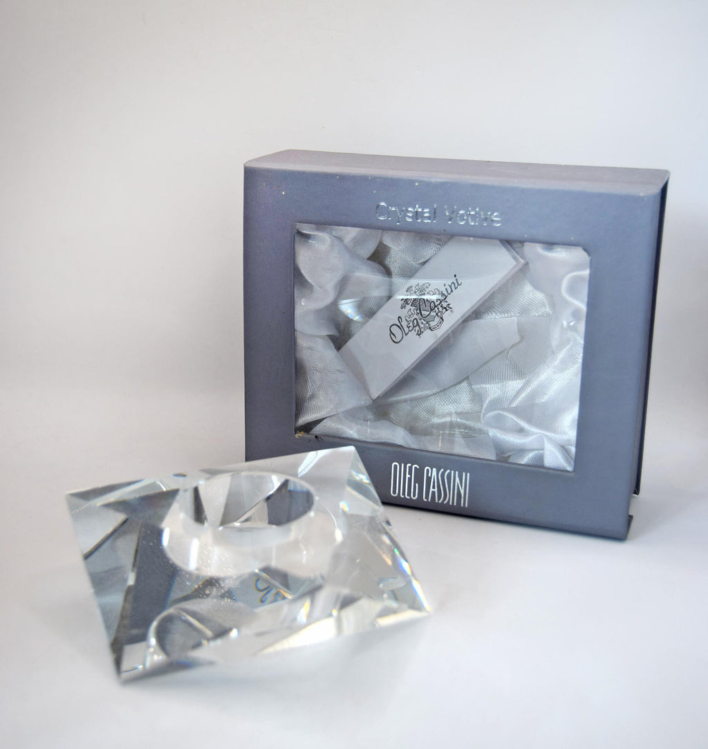 multi-faceted geometric design that beautifully catches and refracts candlelight. It bears the etched, signed "Oleg Cassini" signature on the base and comes safely nestled inside its original sleek gray, satin-lined presentation box.