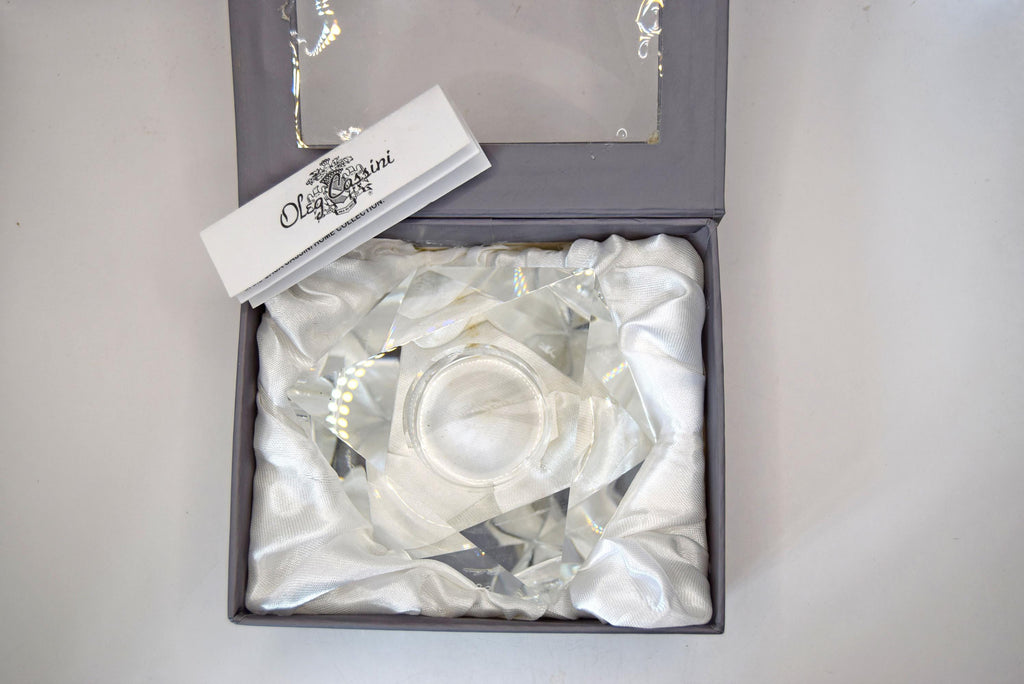 multi-faceted geometric design that beautifully catches and refracts candlelight. It bears the etched, signed "Oleg Cassini" signature on the base and comes safely nestled inside its original sleek gray, satin-lined presentation box.