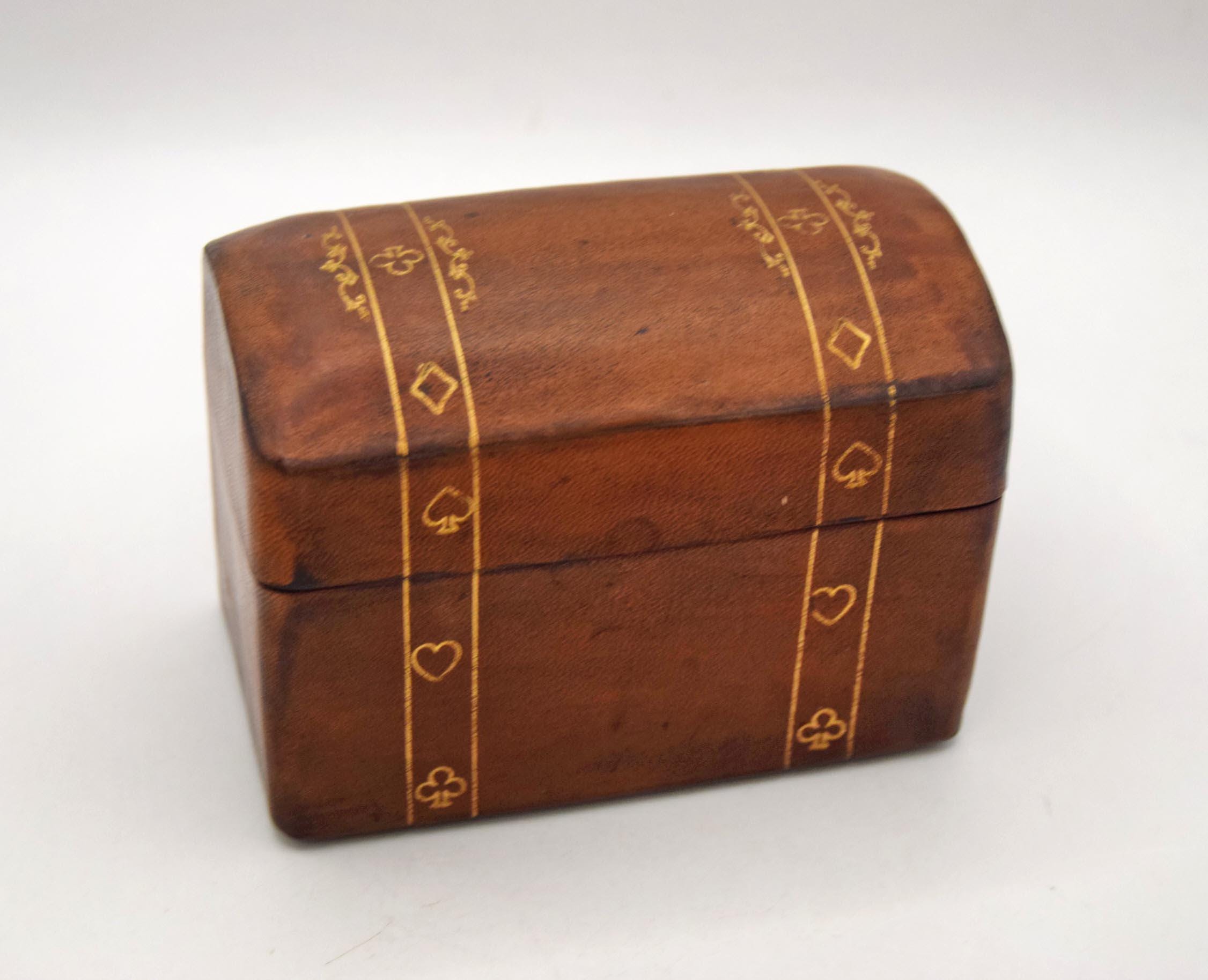 A small rectangular wooden keepsake box with a hinged lid, decorated with gold-colored inlaid patterns of hearts, diamonds, and clubs on a white background.