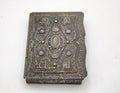 An antique silver-toned embossed case with ornate floral detailing and a central oval motif, photographed on a plain white background.