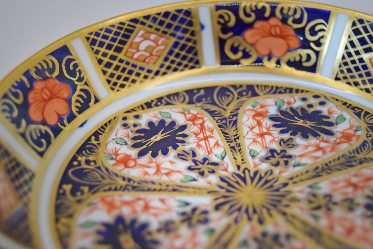 Royal Crown Derby fine bone china small pin dish (trinket dish/butter pat) in the iconic Old Imari 1128 pattern. This piece features the famous rich cobalt blue, iron-red floral motifs, and hand-applied 22-karat gold gilding.