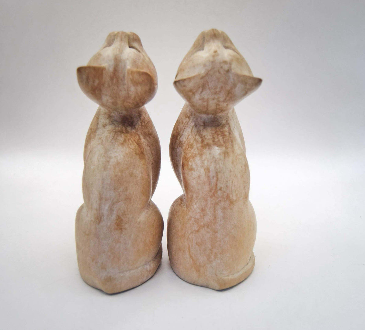 Pair of Vintage Hand-Carved Wooden Cat Figurines. Beautiful pair of stylized, hand-carved wooden cat statues. Crafted with a beautiful minimalist form, these feline companions feature elegantly curved necks and an upward-gazing expression that captures the curious nature of cats.