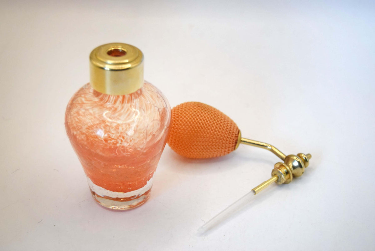 Caithness Glass perfume atomiser. Hand-blown in Scotland, this beautiful piece features a vibrant orange swirl crackle pattern captured within heavy, crystal-clear art glass. It is completed with its original gold-toned metal spray mechanism and a matching knitted orange squeeze bulb.
