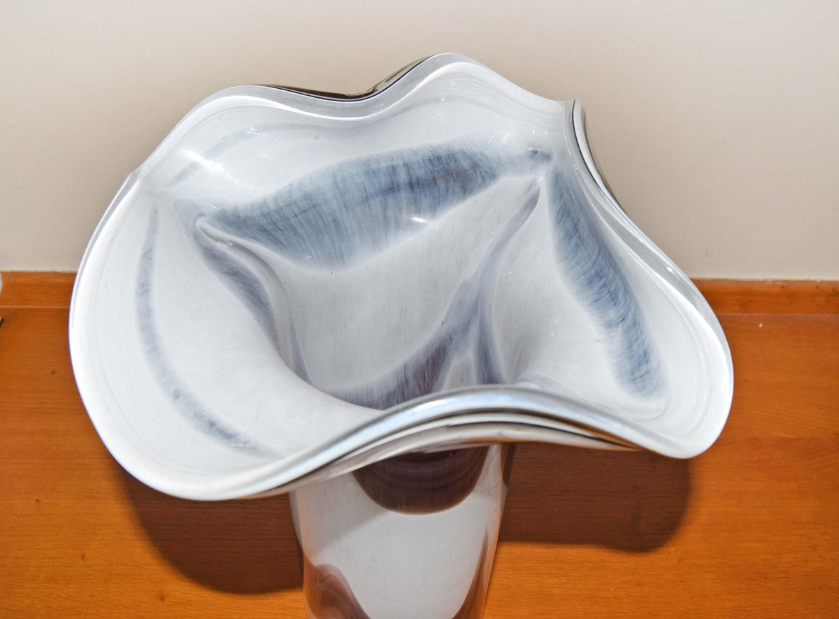 Crafted in a stunning marbled style, the vase showcases a vibrant contrast of an opaque opaline white interior layered with fluid, vertical feather swirls of rich tortoiseshell brown, amber, and beige tones. Each piece is completely unique due to the artisan glassblowing process.