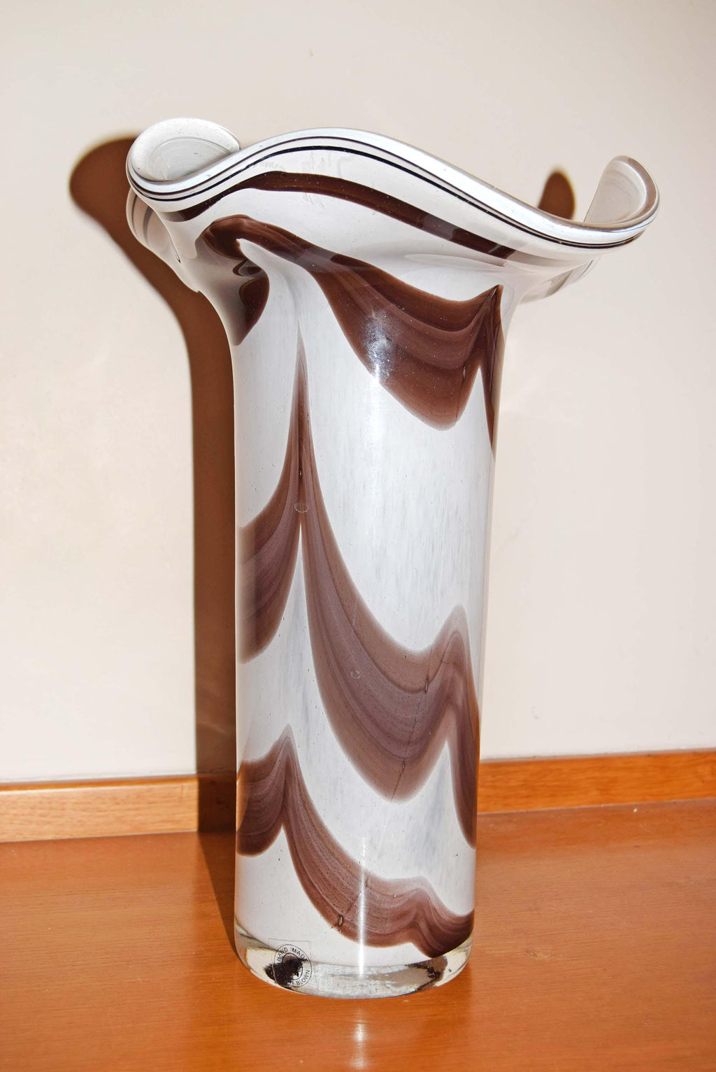 Crafted in a stunning marbled style, the vase showcases a vibrant contrast of an opaque opaline white interior layered with fluid, vertical feather swirls of rich tortoiseshell brown, amber, and beige tones. Each piece is completely unique due to the artisan glassblowing process.
