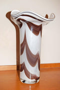 Crafted in a stunning marbled style, the vase showcases a vibrant contrast of an opaque opaline white interior layered with fluid, vertical feather swirls of rich tortoiseshell brown, amber, and beige tones. Each piece is completely unique due to the artisan glassblowing process.
