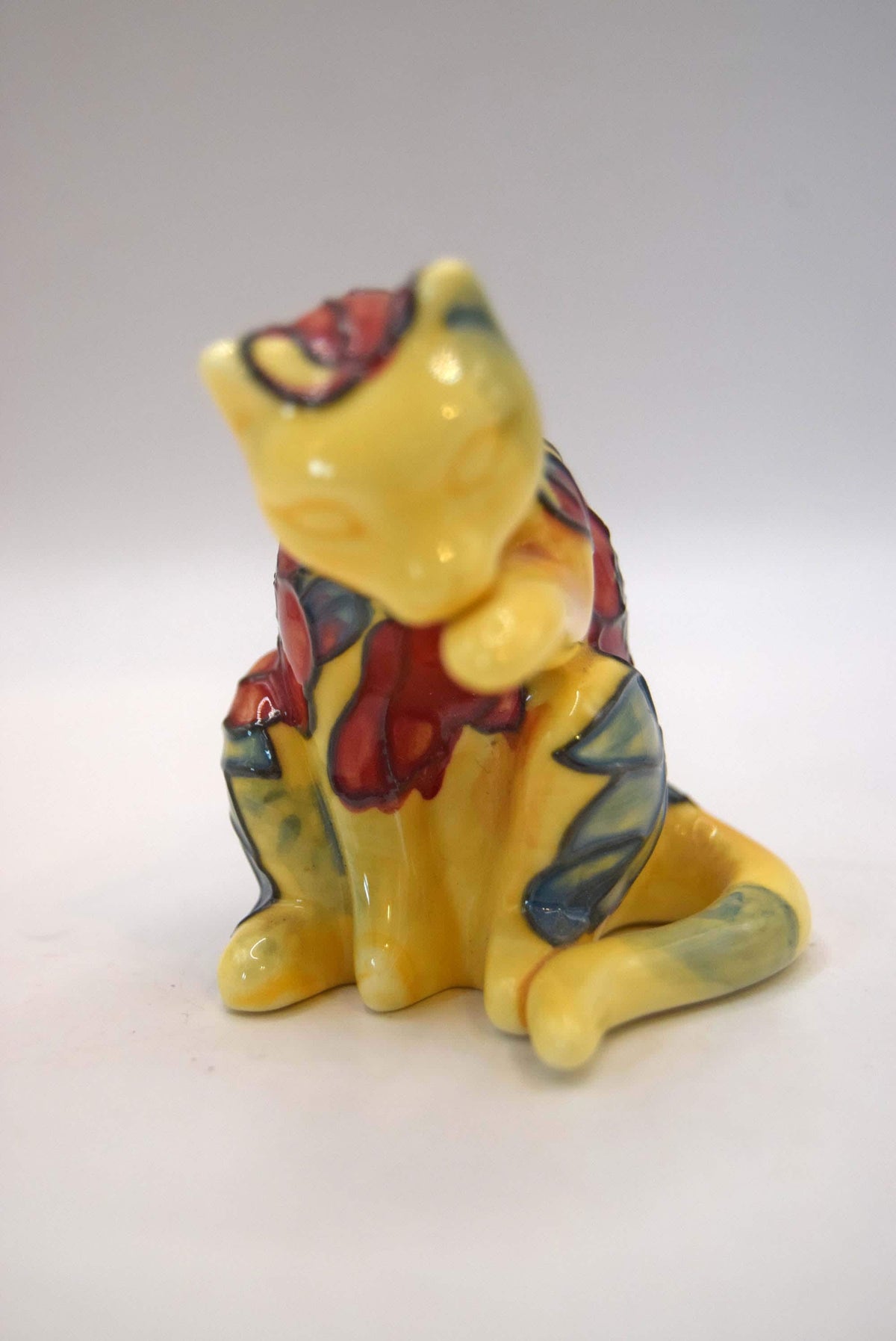 Old Tupton Ware ceramic cat figurine. Beautifully crafted, this piece features a whimsical sitting cat caught in a classic grooming pose, washing its paw.